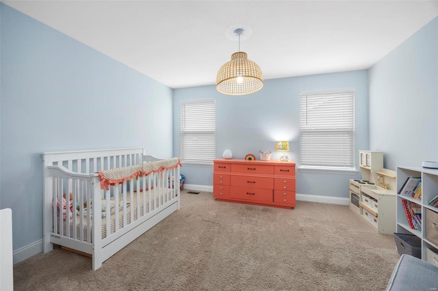 carpeted bedroom featuring baseboards and a crib