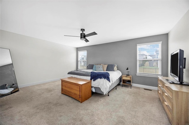 bedroom featuring visible vents, light colored carpet, baseboards, and ceiling fan