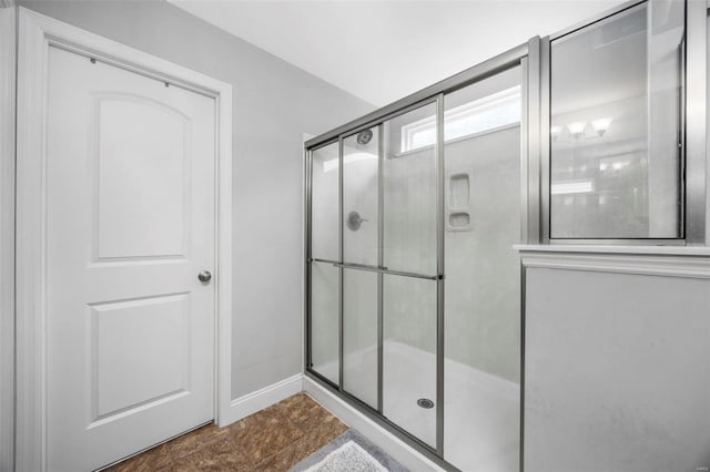 bathroom with a shower stall and baseboards