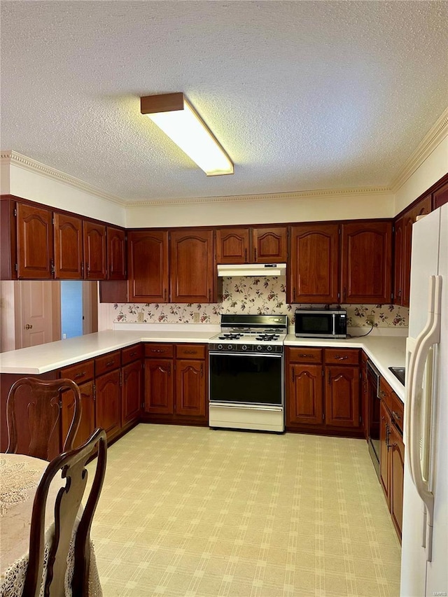 kitchen with gas range, stainless steel microwave, freestanding refrigerator, a peninsula, and light countertops