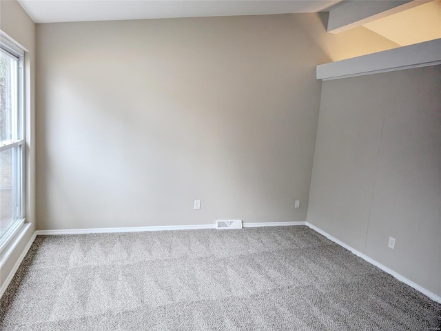 spare room with light carpet, lofted ceiling with beams, visible vents, and baseboards