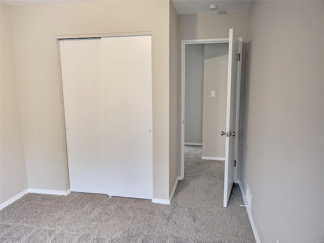 unfurnished bedroom with baseboards, a closet, and light colored carpet