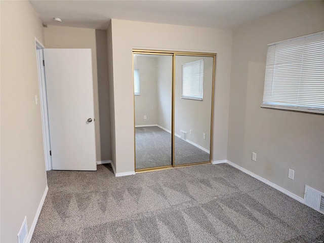 unfurnished bedroom with carpet, a closet, visible vents, and baseboards