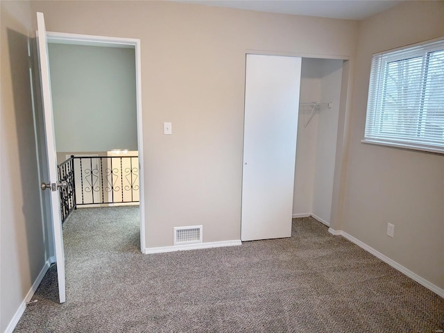 unfurnished bedroom featuring carpet floors, baseboards, visible vents, and a closet