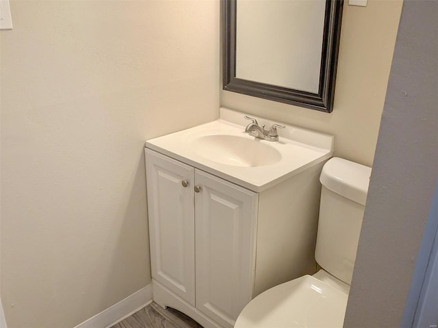 bathroom featuring toilet, baseboards, and vanity