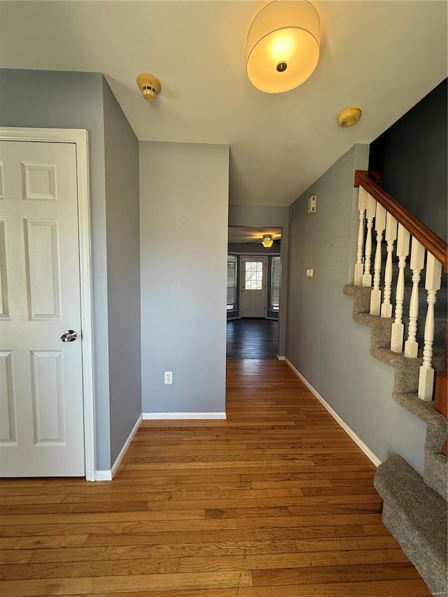 hall featuring stairs, baseboards, and wood finished floors