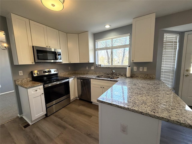 kitchen with stainless steel appliances, a peninsula, a sink, and white cabinets