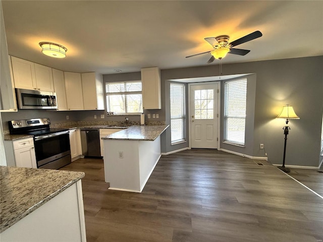 kitchen with stainless steel appliances, white cabinets, a peninsula, and dark wood-type flooring