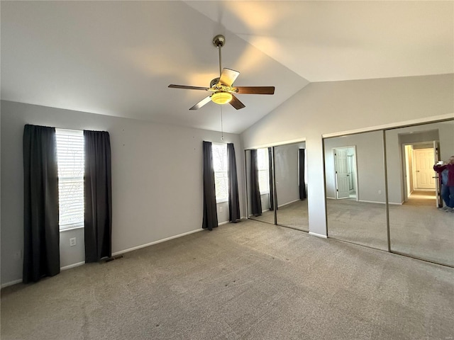 unfurnished bedroom with lofted ceiling, carpet floors, baseboards, and multiple closets