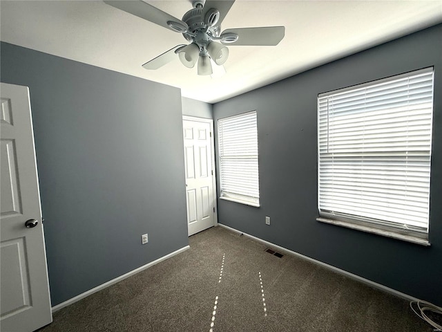 empty room featuring a ceiling fan, carpet, visible vents, and baseboards