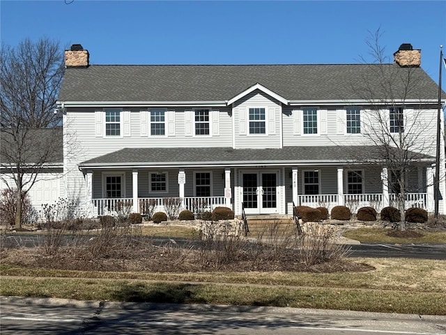 view of front of property featuring covered porch, a chimney, and roof with shingles