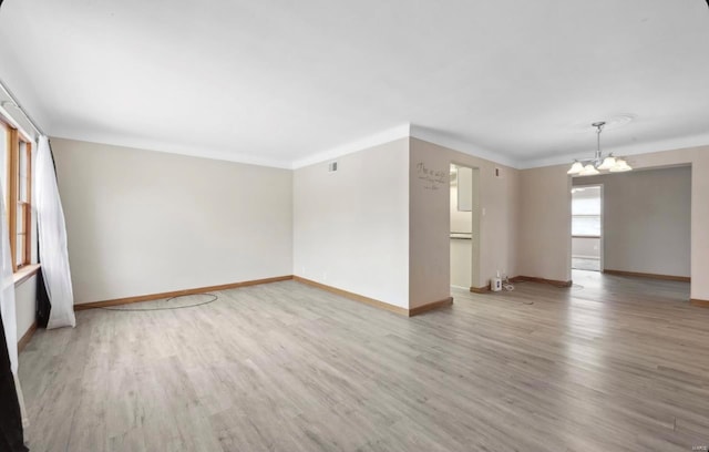 unfurnished room featuring baseboards, an inviting chandelier, wood finished floors, and ornamental molding