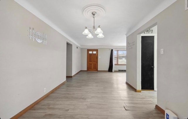 corridor with baseboards, light wood-style floors, and a chandelier