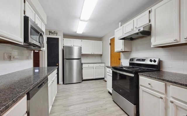 kitchen with under cabinet range hood, decorative backsplash, appliances with stainless steel finishes, light wood-style floors, and white cabinetry