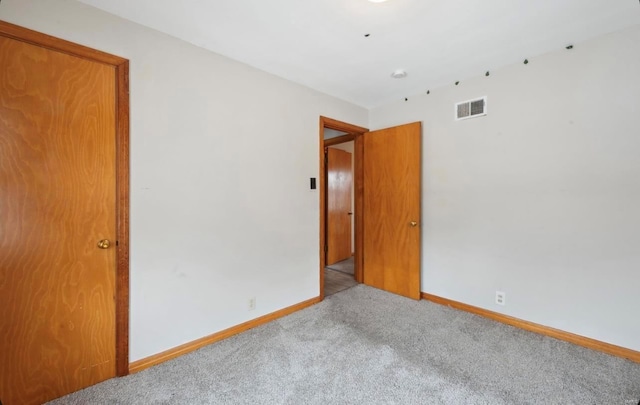 carpeted empty room with visible vents and baseboards