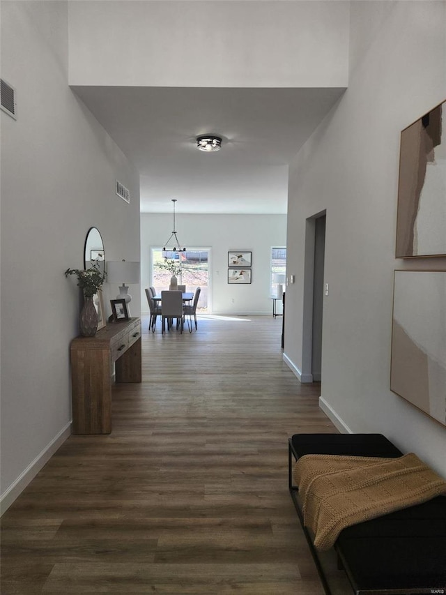 hall featuring visible vents, dark wood-style flooring, and baseboards