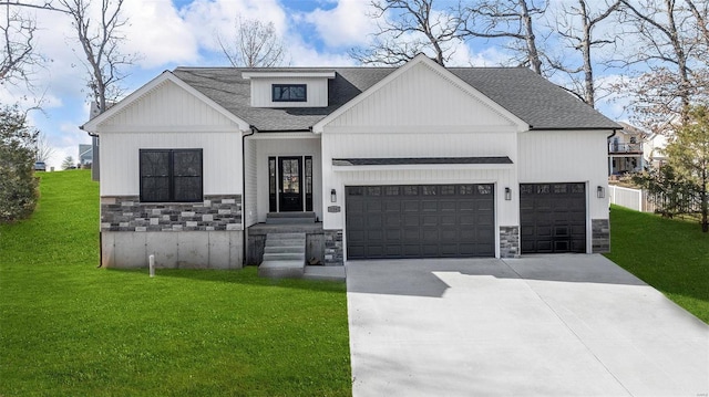 modern farmhouse featuring a shingled roof, concrete driveway, a front yard, a garage, and stone siding