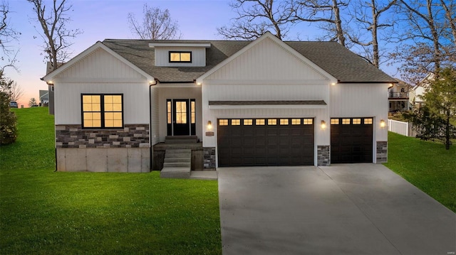 modern farmhouse style home with stone siding, a lawn, concrete driveway, and a garage