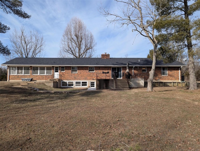 back of house featuring brick siding, a chimney, and a lawn