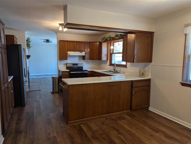 kitchen featuring dark wood finished floors, light countertops, appliances with stainless steel finishes, a peninsula, and under cabinet range hood