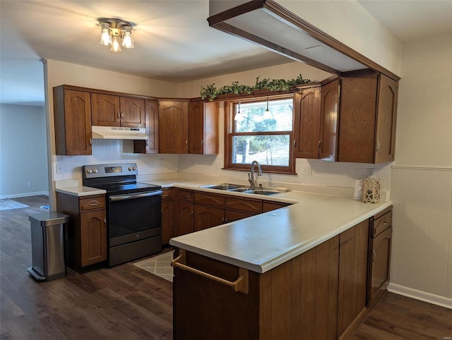 kitchen featuring dark wood-style flooring, light countertops, stainless steel range with electric cooktop, under cabinet range hood, and a sink