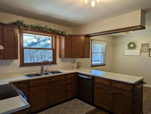 kitchen with a wealth of natural light, dishwasher, a peninsula, light countertops, and a sink