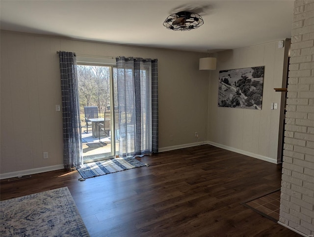 unfurnished room featuring dark wood-style floors, visible vents, and baseboards