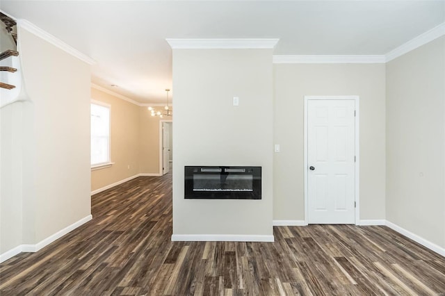 spare room with dark wood-style floors, baseboards, crown molding, and a glass covered fireplace