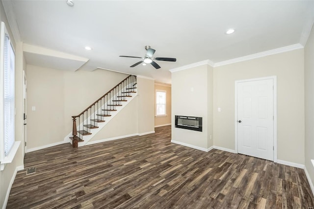 unfurnished living room with wood finished floors, baseboards, stairs, ornamental molding, and a glass covered fireplace