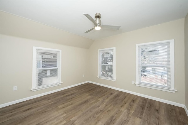 spare room featuring lofted ceiling, dark wood-type flooring, a ceiling fan, and baseboards