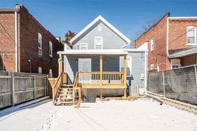 snow covered rear of property with central AC unit, fence, and a porch