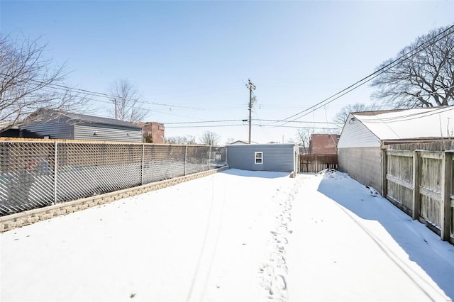 yard layered in snow featuring a fenced backyard and an outdoor structure