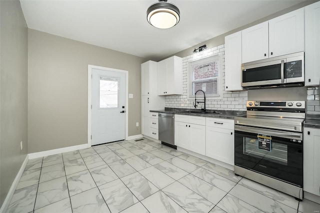 kitchen featuring dark countertops, a sink, marble finish floor, stainless steel appliances, and backsplash