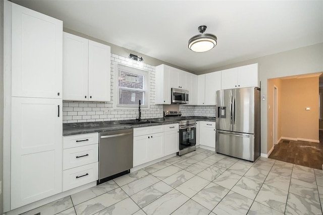 kitchen featuring a sink, white cabinets, marble finish floor, appliances with stainless steel finishes, and dark countertops