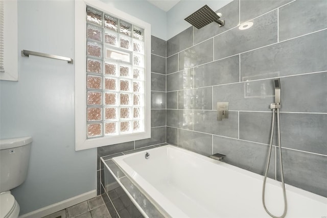 bathroom with a tub to relax in, toilet, a tile shower, baseboards, and tile patterned floors