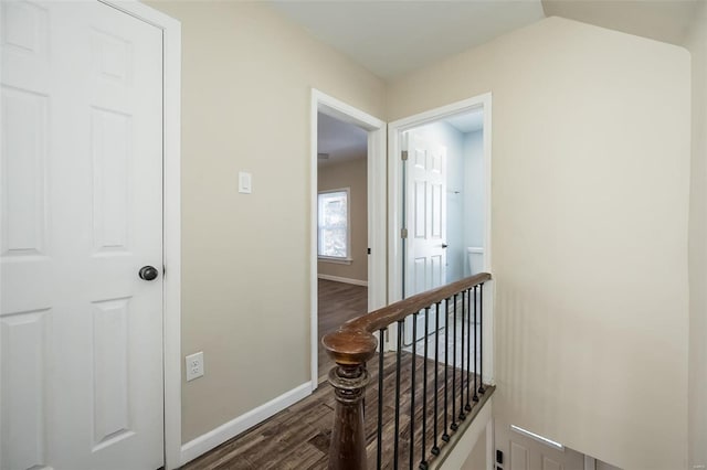 corridor featuring dark wood finished floors, an upstairs landing, and baseboards