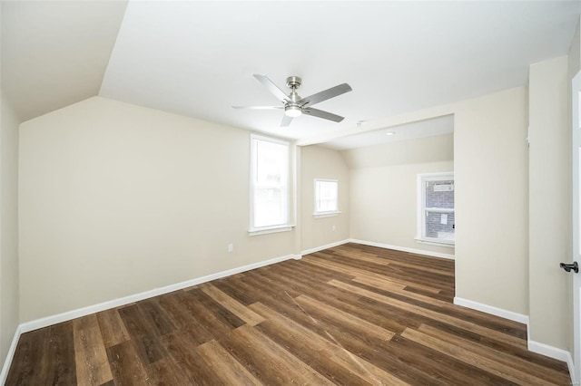 unfurnished room with vaulted ceiling, dark wood-style floors, a ceiling fan, and baseboards