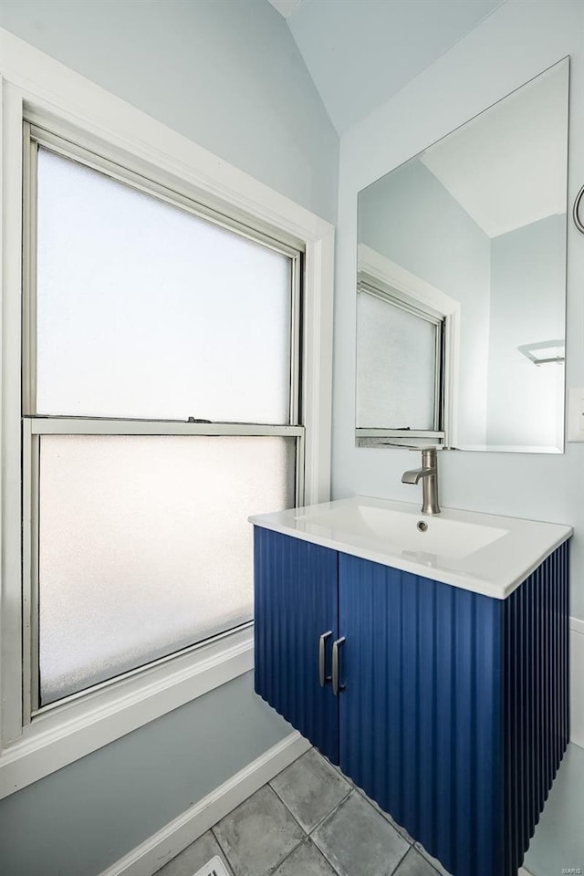 bathroom featuring lofted ceiling, baseboards, vanity, and tile patterned floors