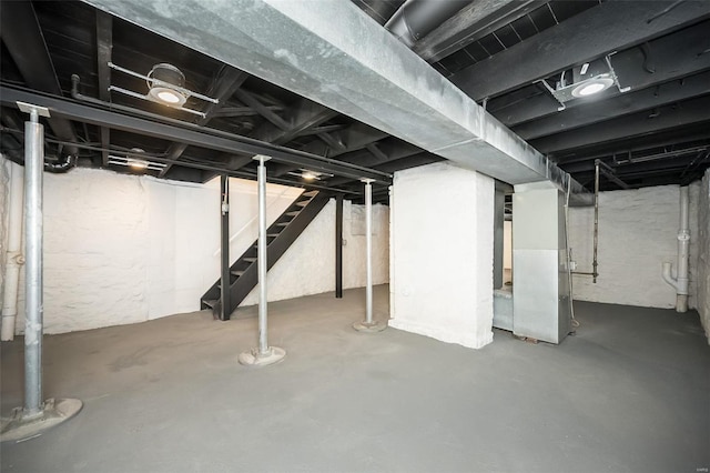 unfinished basement featuring stairway and heating unit