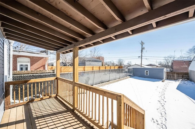 snow covered deck featuring an outdoor structure and a fenced backyard