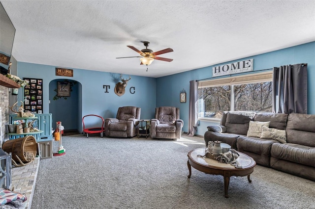 living room featuring carpet floors, ceiling fan, arched walkways, and a textured ceiling