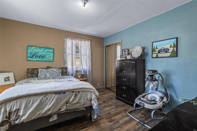 bedroom with dark wood-type flooring, a closet, and baseboards