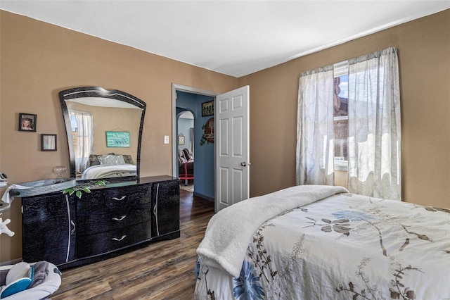 bedroom featuring dark wood-style floors and arched walkways