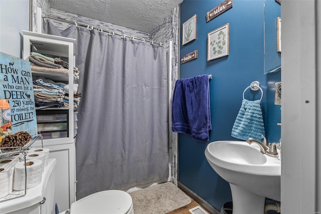 bathroom featuring curtained shower, visible vents, a textured ceiling, and toilet