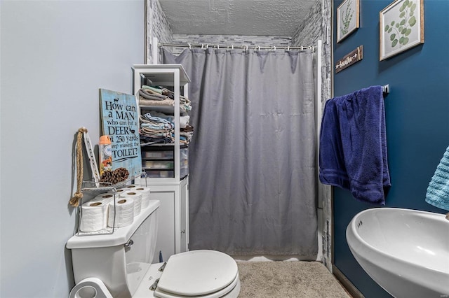 bathroom with a shower with shower curtain, a sink, a textured ceiling, and toilet