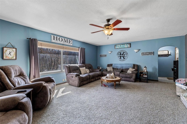 living room with baseboards, arched walkways, a ceiling fan, a textured ceiling, and carpet floors