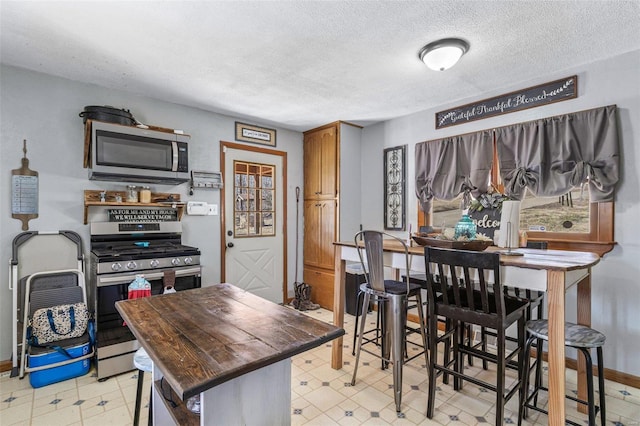 kitchen featuring a textured ceiling, stainless steel appliances, and light floors