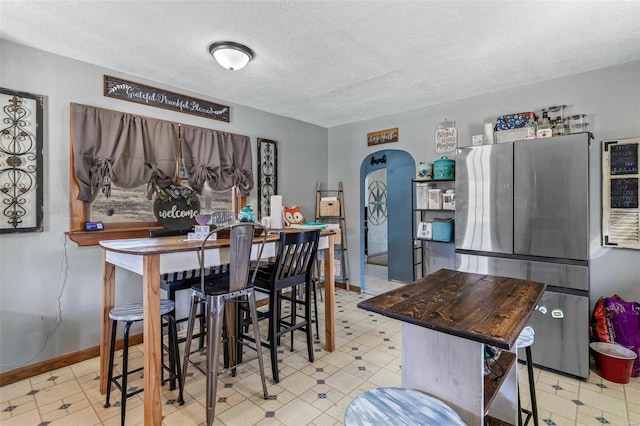 dining area with arched walkways, a textured ceiling, and tile patterned floors