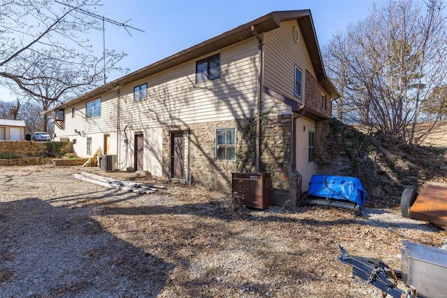 back of property featuring central AC and stone siding