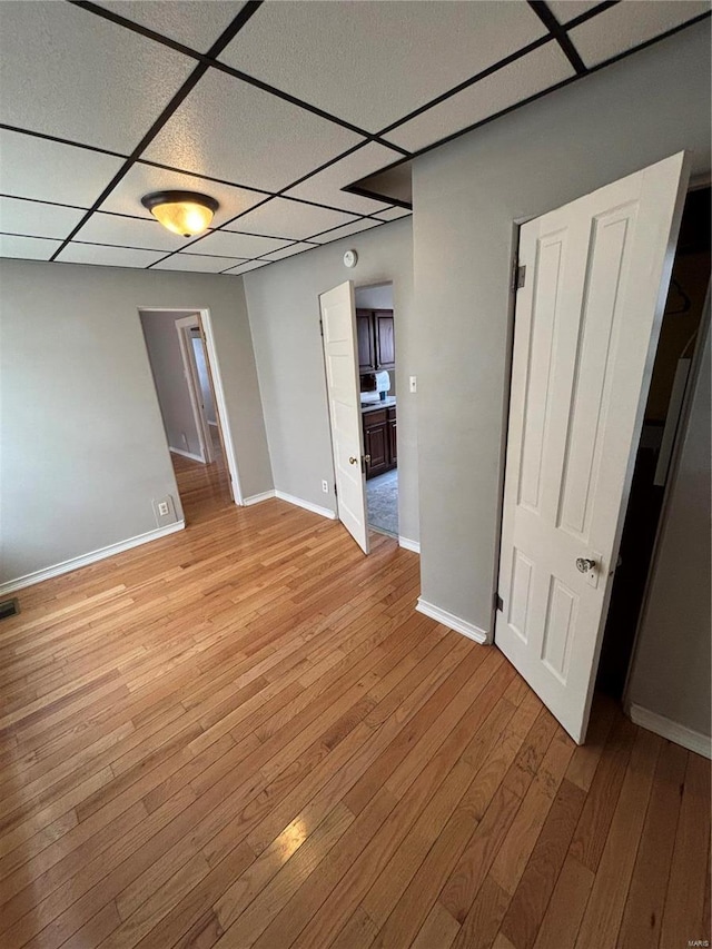 spare room with light wood-style flooring, visible vents, baseboards, and a drop ceiling